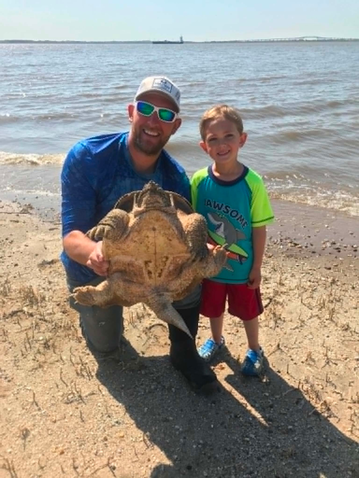 Father and son with a large snapping turtle